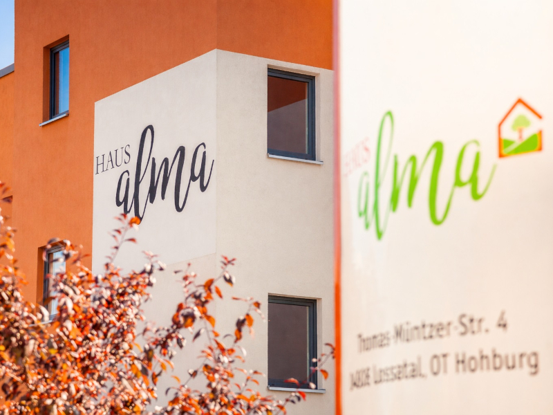 Nahaufnahme weiß orangenes Haus mit Aufschrift Haus Alma